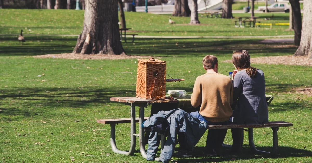 Couple having lunch at a picnic table in a park